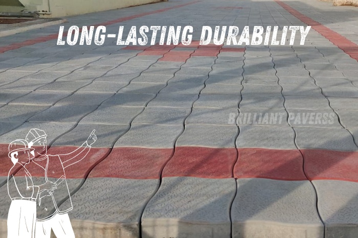 Neatly arranged gray and red paver blocks with the caption "LONG-LASTING DURABILITY," accompanied by an illustration of two construction workers pointing ahead, highlighting the robust and enduring paver solutions provided by Brilliant Paverss, Coimbatore’s trusted name for high-quality and durable paving blocks