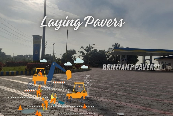 Wide-open area paved with colorful paver blocks at a fuel station, featuring the text "Laying Pavers" and construction-themed illustrations, highlighting Brilliant Paverss' professional paver laying services and expertise in creating durable and visually appealing paved surfaces in Coimbatore